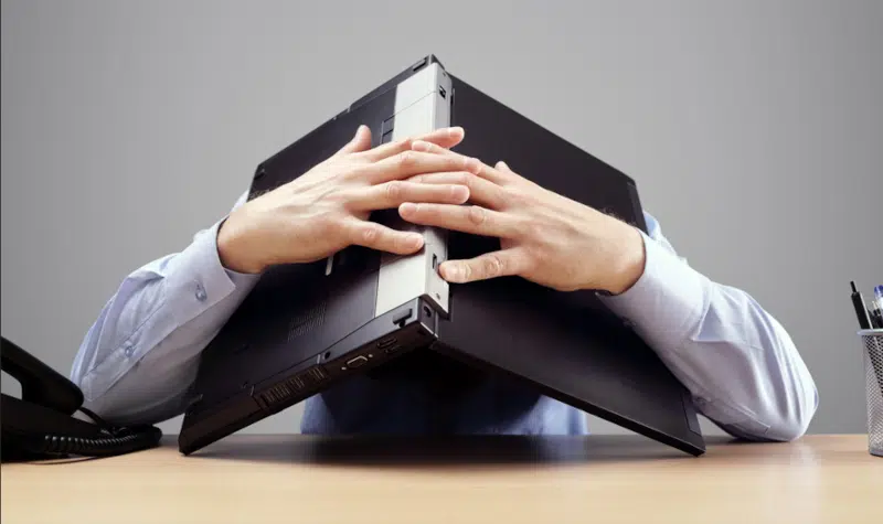 man using computer to cover his head.
