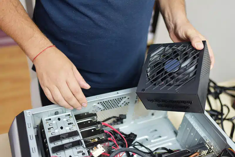 a repairman replaces the power supply in the computer